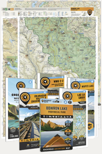 Multiple folded backcountry maps and a topographic map spread out, showing contour lines, trail routes, and map scale legends.